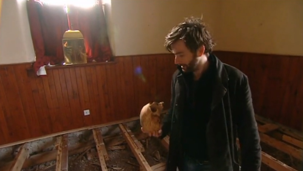 Kadr z „Who Do You Think You Are” z Davidem Tennantem, który trzyma w dłoni czaszkę.